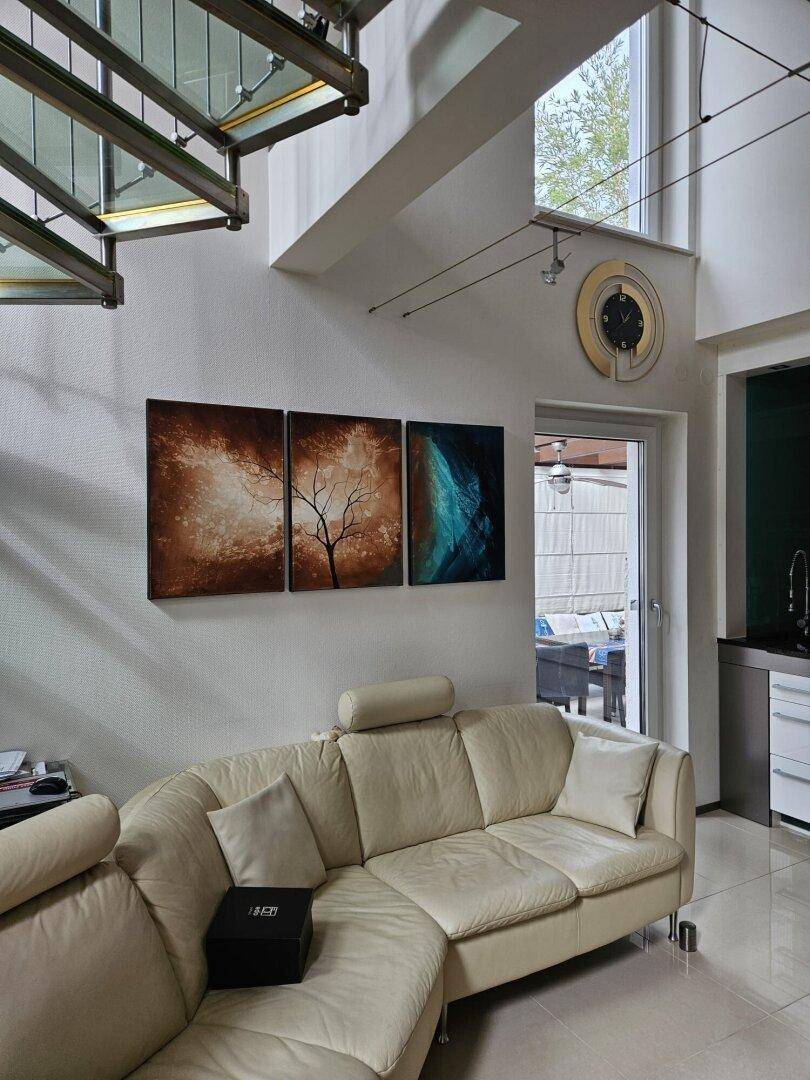 Heller Wohnbereich mit beigem Sofa, Fliesenboden und Zugang zu einem Außenbereich.