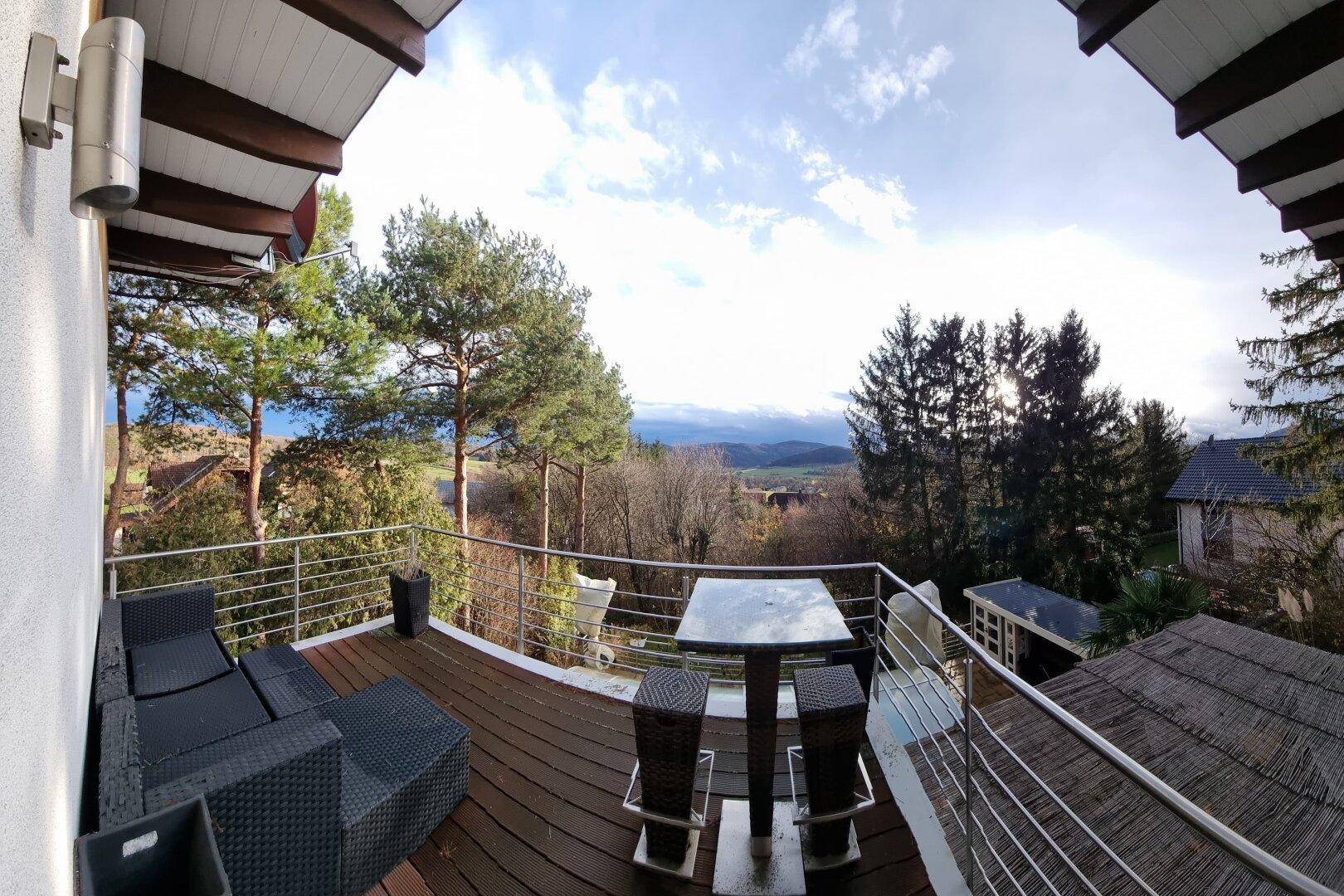 Großer Balkon mit Sitzgelegenheiten und weitem Blick auf die Landschaft und Berge.