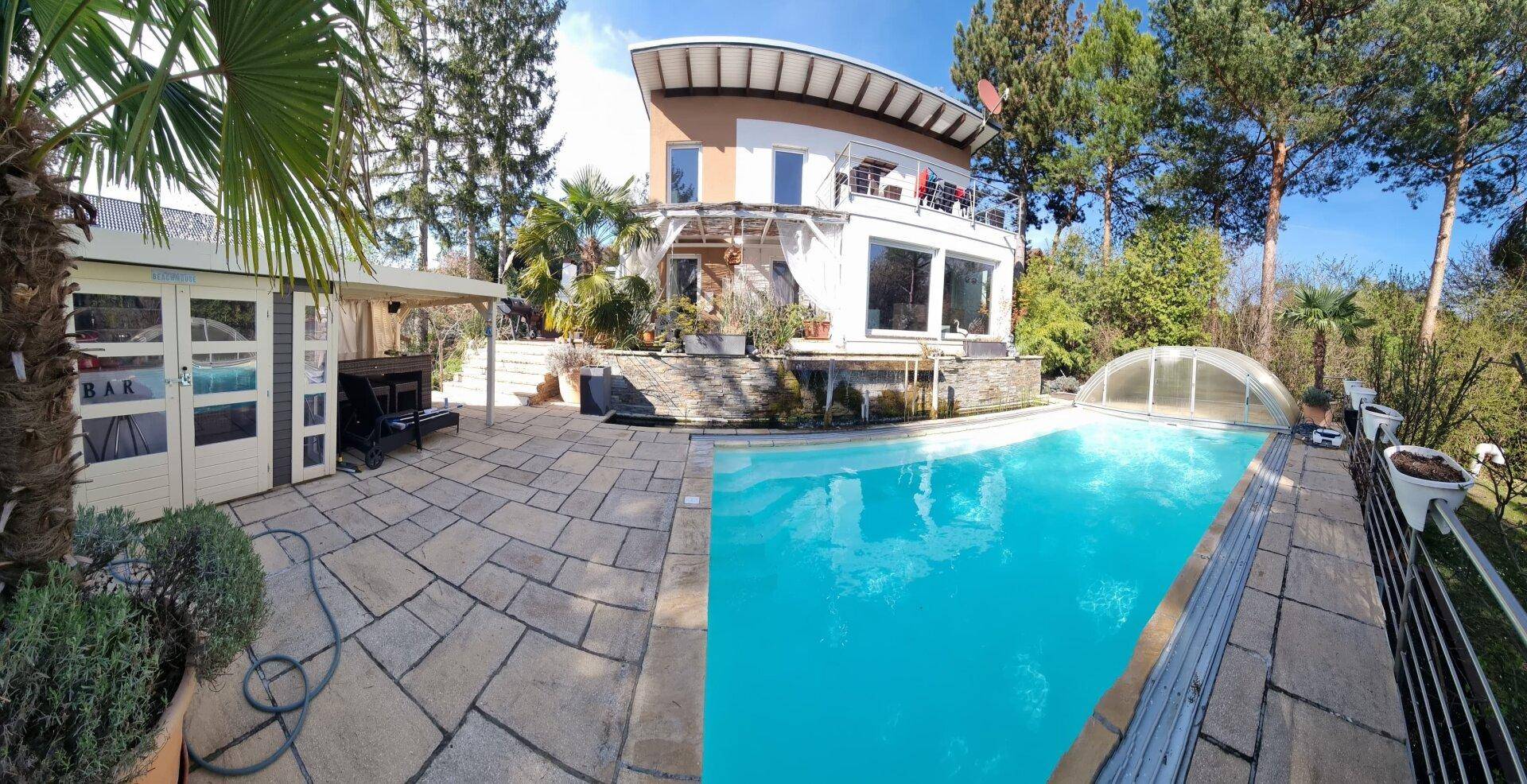 Großzügiger Garten mit Pool, Bar und gepflasterter Fläche vor dem Haus.