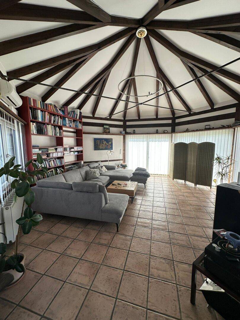 Helles Wohnzimmer mit großem Sofa, Bücherregal und Terrakottafliesen, ideal zum Entspannen.