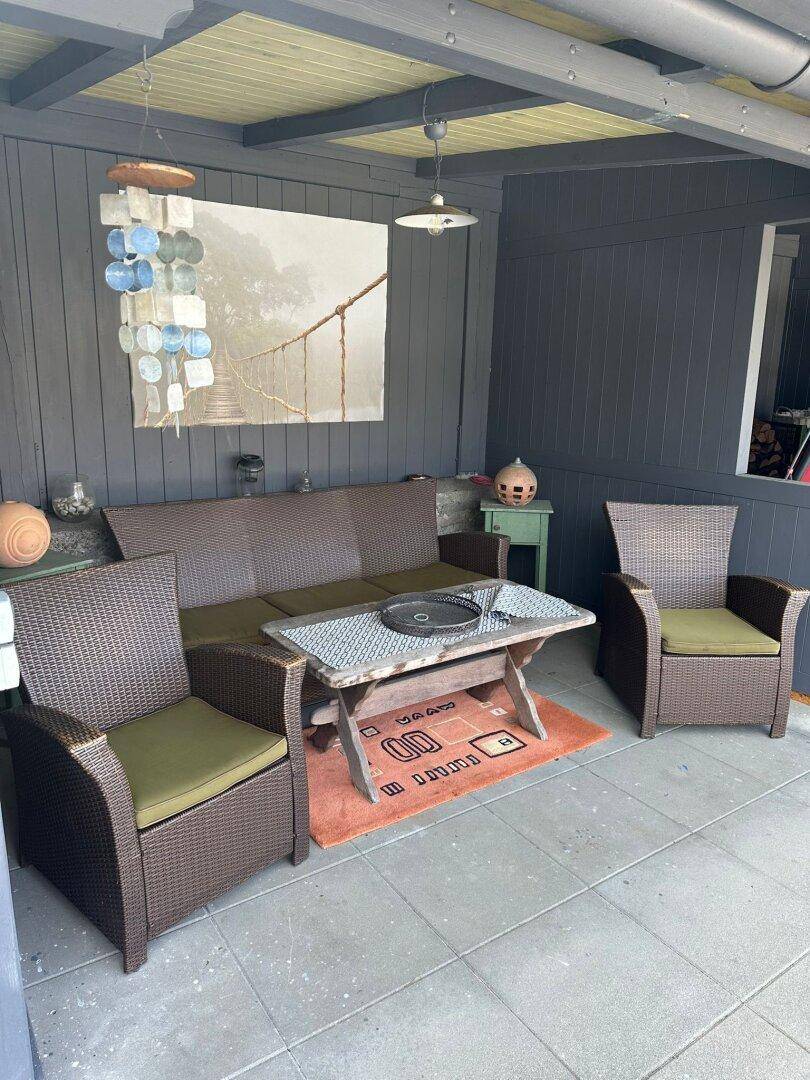 Gemütliche überdachte Terrasse mit Rattanmöbeln und einem Holztisch für entspannte Stunden.