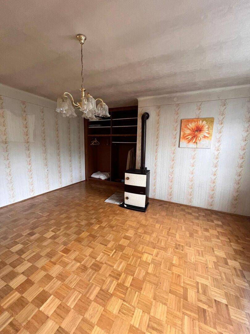 Schlafzimmer mit Parkettboden, einem Holzofen und integriertem Kleiderschrank.
