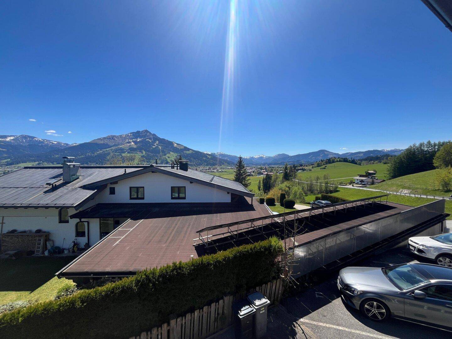 Weitläufiger Blick auf die Immobilie und die umliegende Berglandschaft unter strahlendem Himmel.