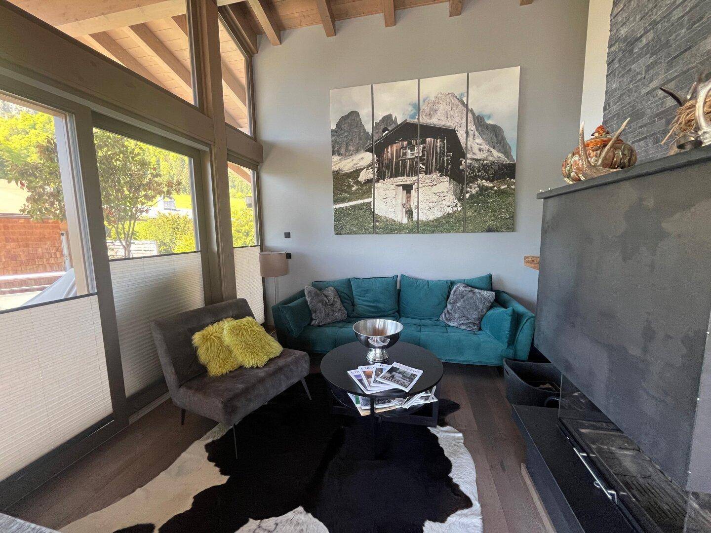 Modernes Wohnzimmer mit tealfarbenem Sofa, Kamin und großformatigem Wandbild.