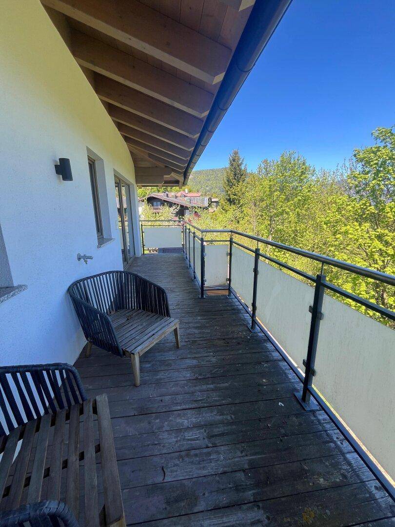 Geräumiger Balkon mit Holzboden und Sitzgelegenheiten, ideal zum Entspannen im Freien.