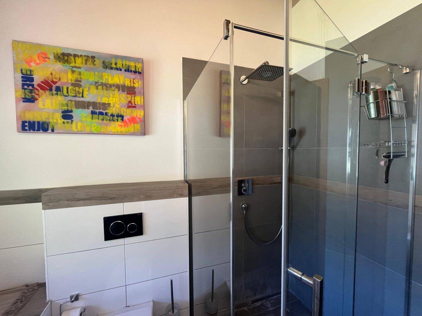 Modernes Badezimmer mit begehbarer Dusche und Wand-WC, ausgestattet mit zeitgenössischer Kunst.