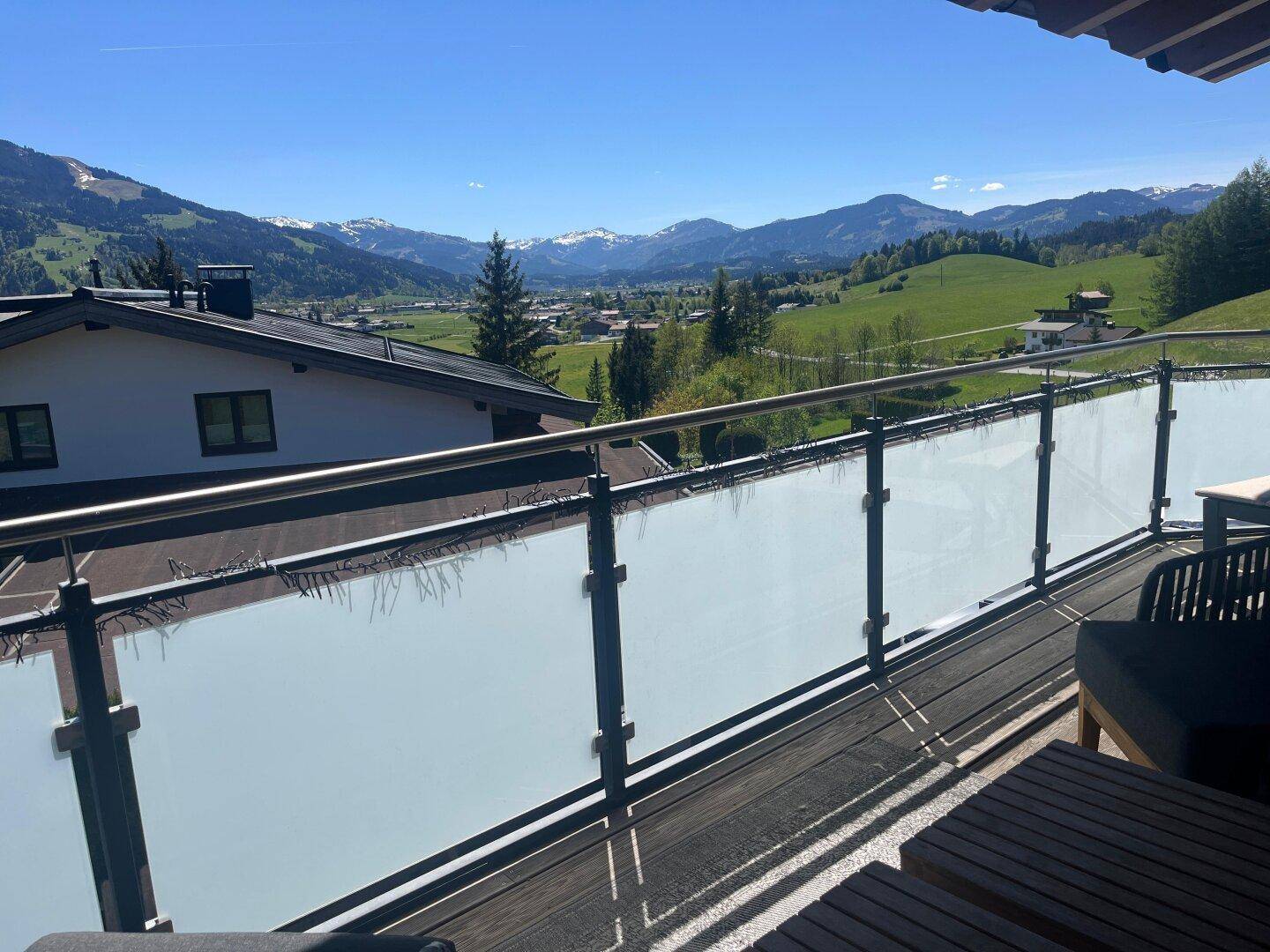 Geräumiger Balkon mit Glasbrüstung und atemberaubendem Panoramablick auf die Berge und das Tal.
