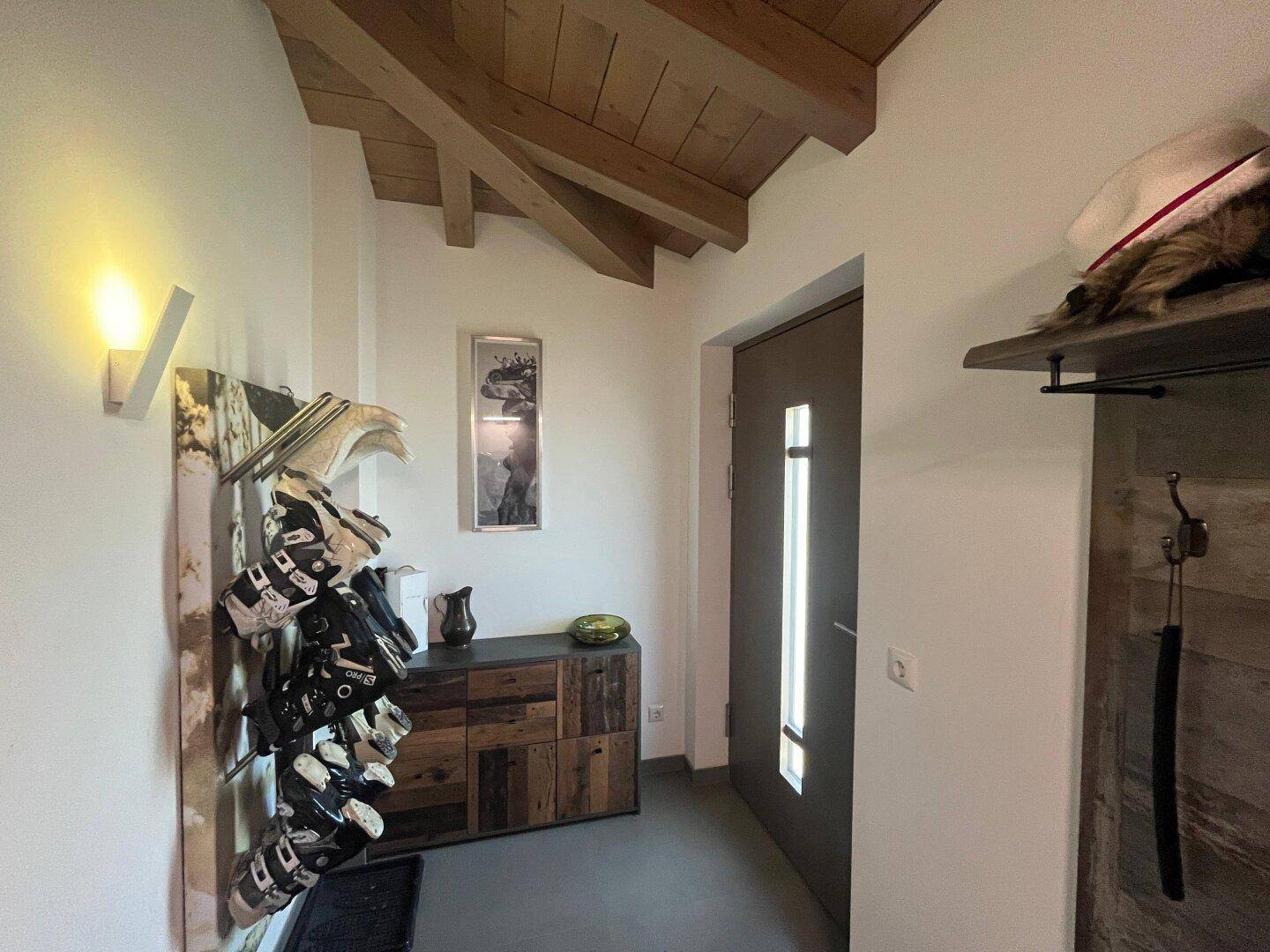 Eingangsbereich mit Holzbalkendecke, Schuhregal und Garderobe, einladend gestaltet.