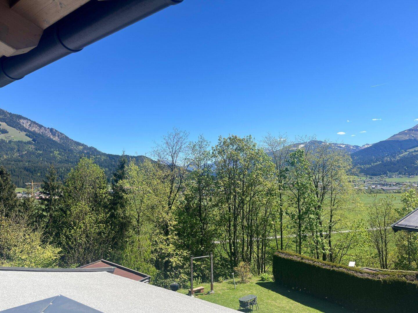 Weitläufiger Blick auf grüne Hügel, Bäume und einen gepflegten Gartenbereich.