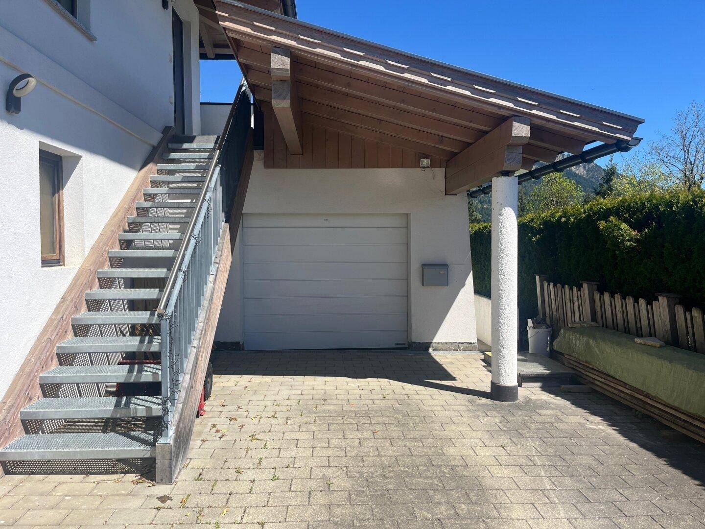 Außenansicht des Hauses mit Garage und Außentreppe, umgeben von Grün.