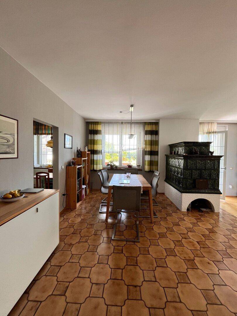 Essbereich mit traditionellem Kachelofen, Terrakotta-Fliesenboden und einem Esstisch.