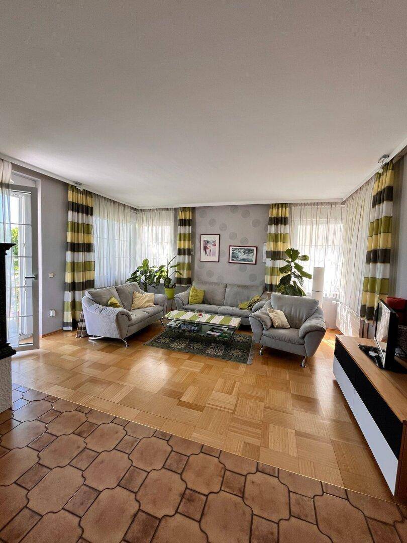 Gemütliches Wohnzimmer mit Parkettboden, bequemen Sofas und farbenfrohen Vorhängen.