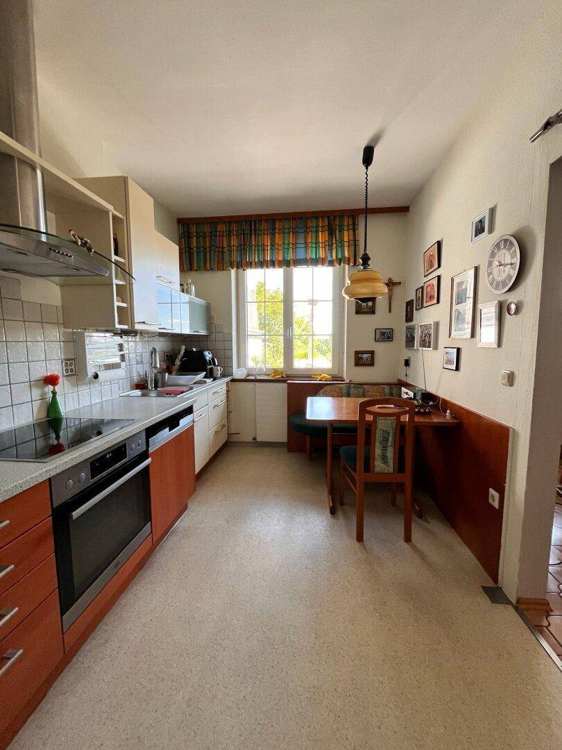Funktionale Küche mit Einbaugeräten, Essbereich und einem Fenster mit Blick ins Grüne.