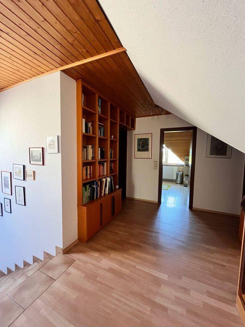 Obergeschoss-Flur mit Holzparkett, eingebautem Bücherregal und Dachschrägen.