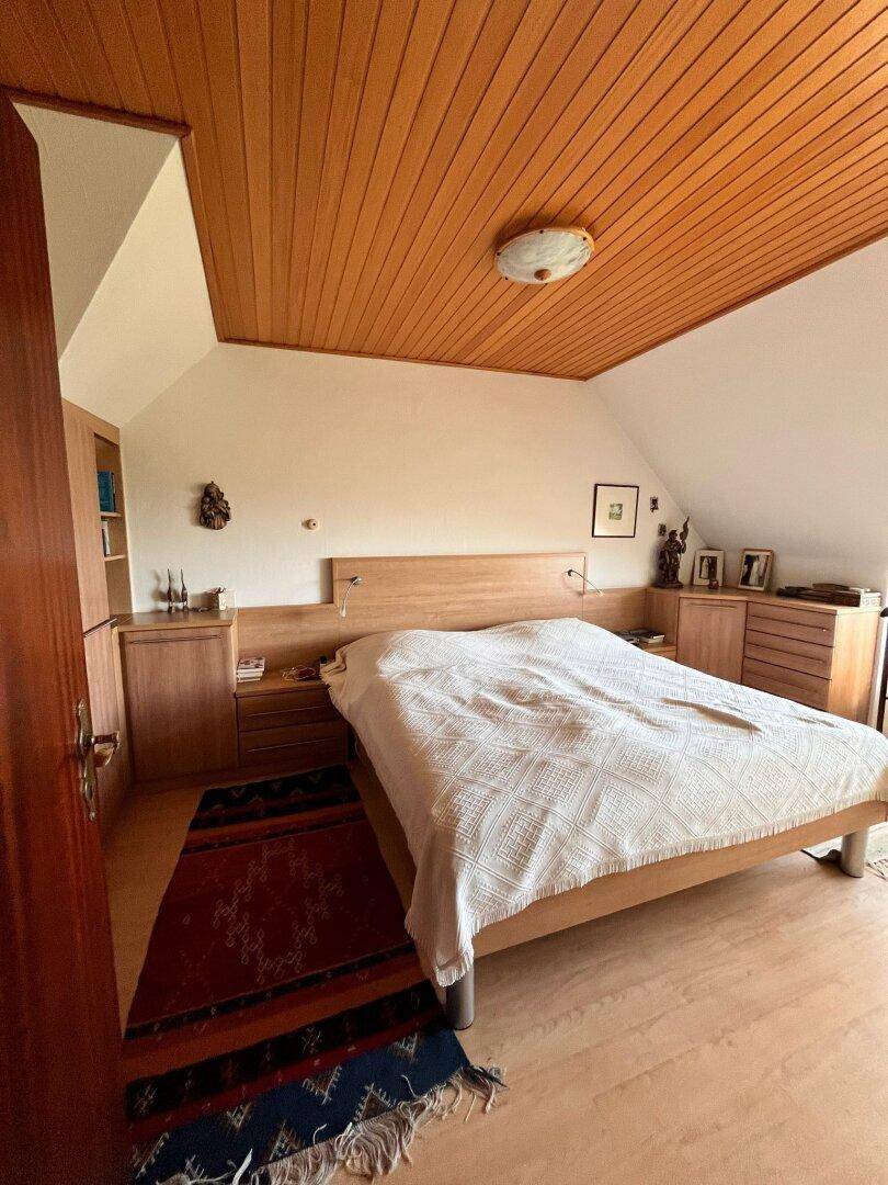 Gemütliches Schlafzimmer im Dachgeschoss mit Holztäfelung, Doppelbett und Dachschrägen.