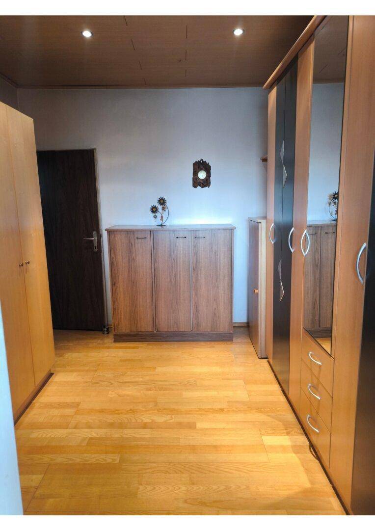 Geräumiger Raum mit hellem Holzfußboden und mehreren Holzschränken für ausreichend Stauraum.