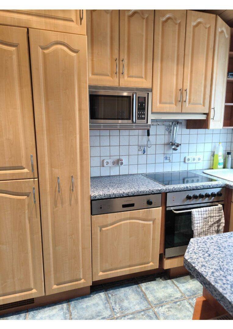 Funktionale Küche mit Holzschränken, integrierten Geräten und Granit-Arbeitsplatten.