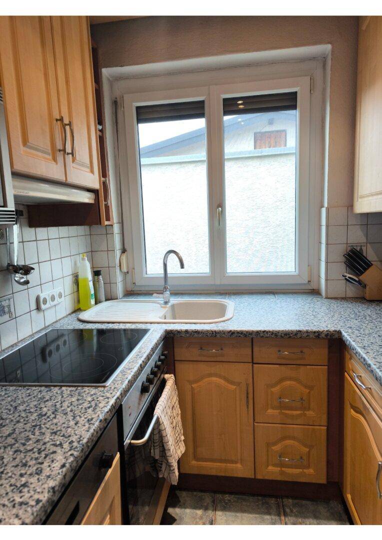 Funktionale Küche mit Holzschränken, Granit-Arbeitsplatten und einem Fenster über der Spüle.