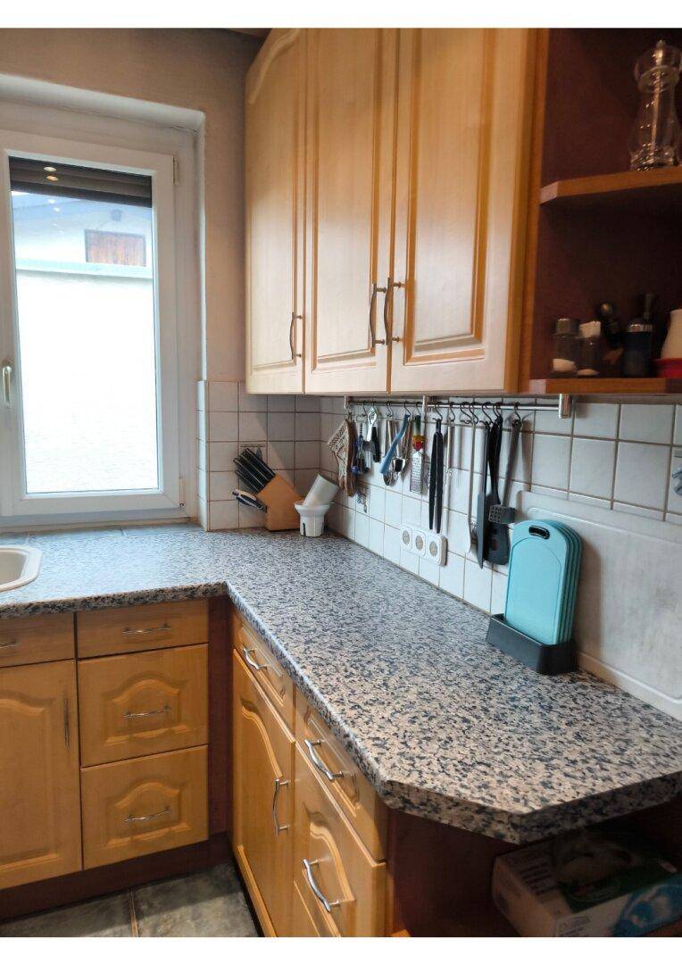 Küchenarbeitsbereich mit Holzschränken, Granit-Arbeitsplatte, Spüle und Küchenutensilien.