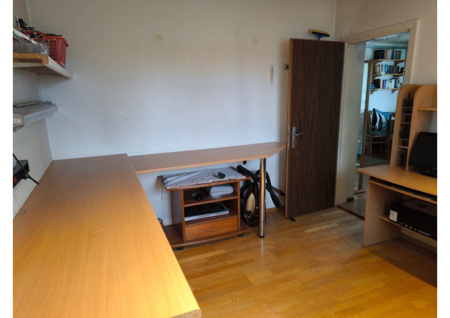 Arbeitszimmer mit Holzboden, langen Schreibtischen und Regalen für Stauraum.