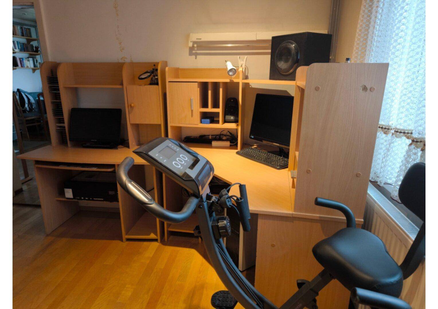 Geräumiges Arbeitszimmer mit mehreren Schreibtischen, Computern und einem Heimtrainer.