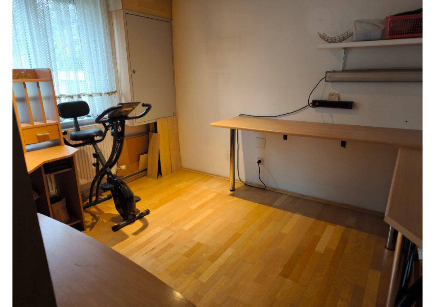 Helles Arbeitszimmer mit Holzboden, Schreibtischen und einem Fenster für Tageslicht.