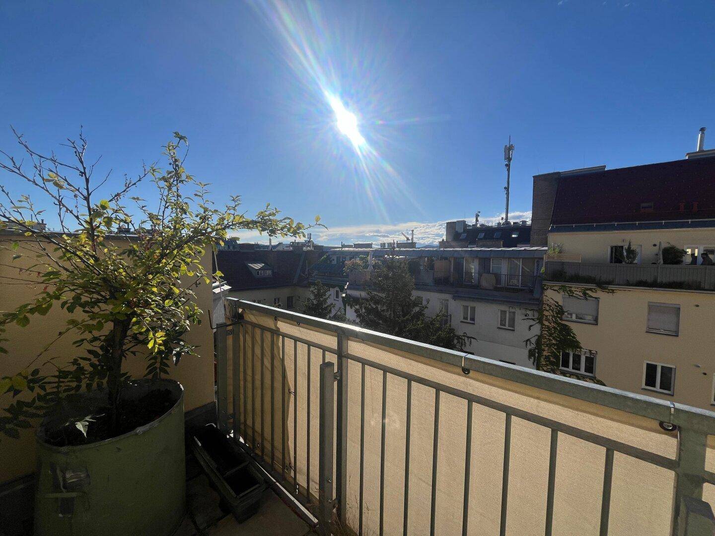 Heller Balkon mit Pflanzen und weitem Blick über die Stadt und die umliegenden Gebäude.