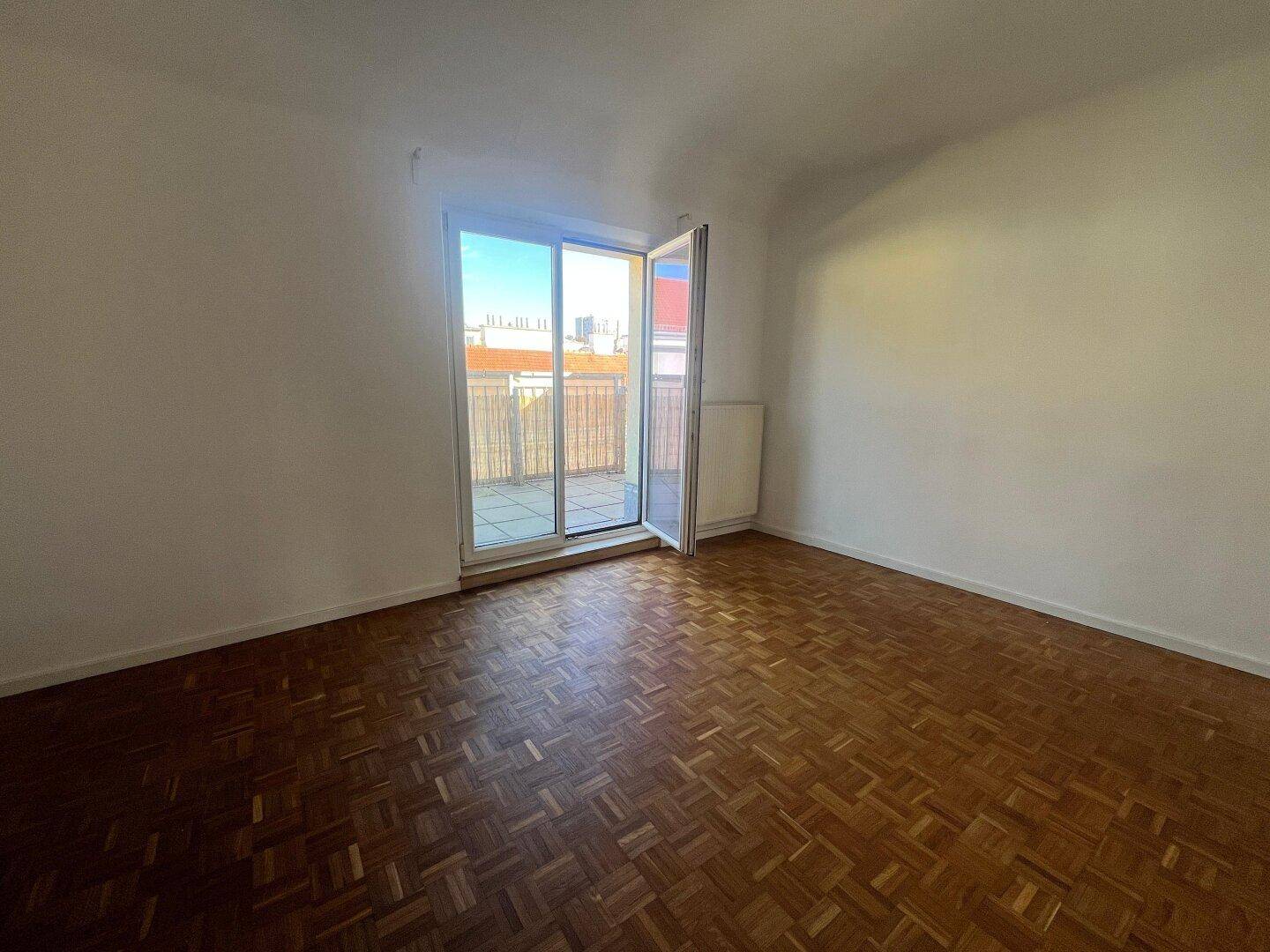 Lichtdurchflutetes Zimmer mit Parkettboden und direktem Zugang zu einem Außenbereich.