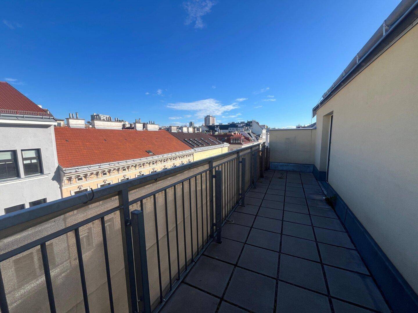 Heller Balkon mit Fliesenboden und freiem Blick auf die Stadtlandschaft.