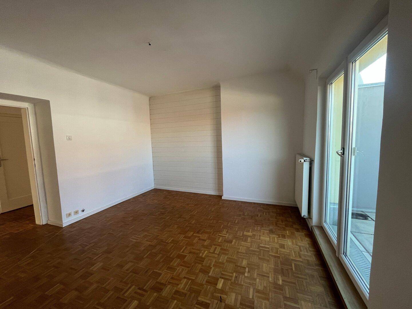 Lichtdurchflutetes Zimmer mit Parkettboden und direktem Zugang zu einem Außenbereich.