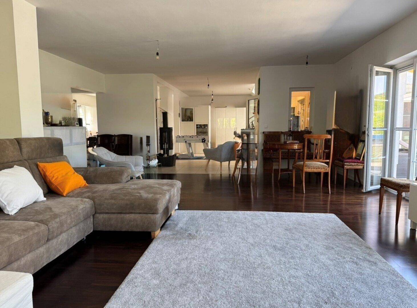Großzügiger offener Wohnbereich mit dunklem Parkettboden und verschiedenen Funktionsbereichen.