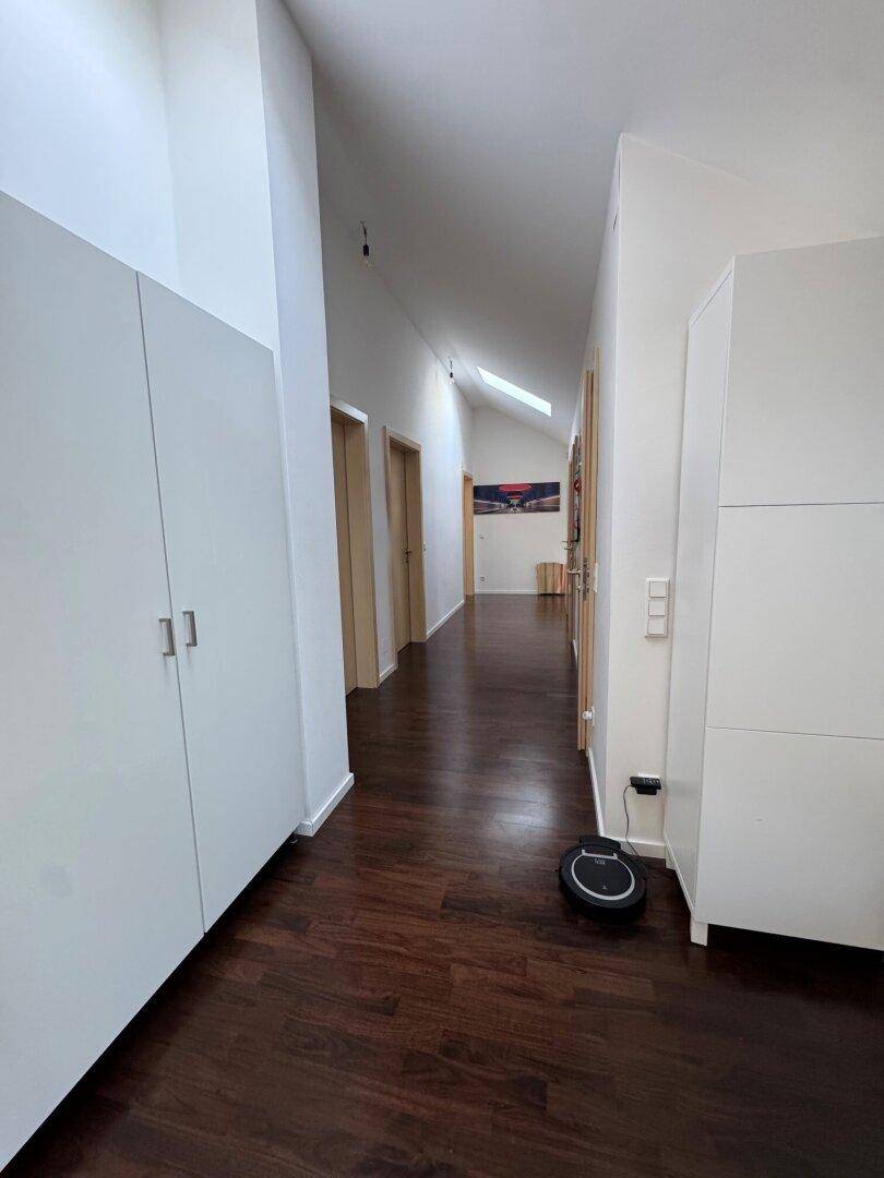 Heller Flur mit dunklem Holzfußboden und integrierten Schränken.