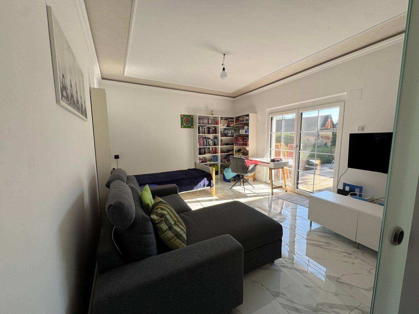 Helles Schlafzimmer mit Zugang zum Garten und modernem Fliesenboden.