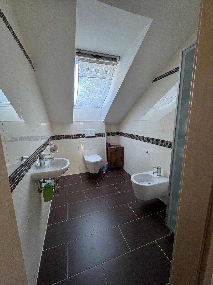 Gäste-WC im Dachgeschoss mit Dachfenster, Waschbecken und Bidet.