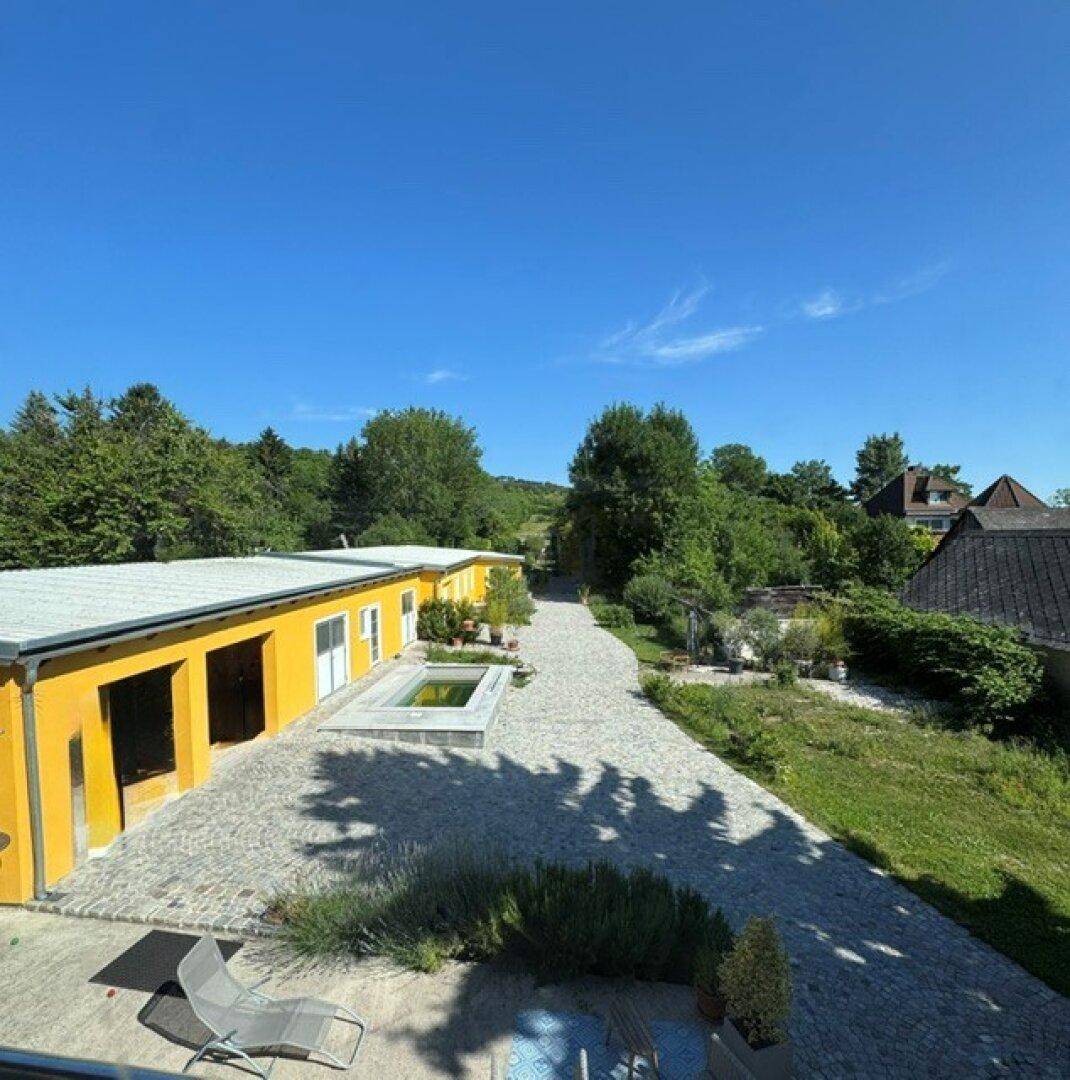 Weitläufiger Außenbereich mit gepflastertem Weg, kleinen Wasserbecken und viel Grün.