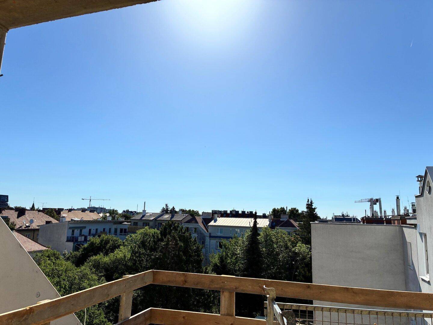 Weitblick über die Stadt von einem im Bau befindlichen Balkon unter klarem blauem Himmel.