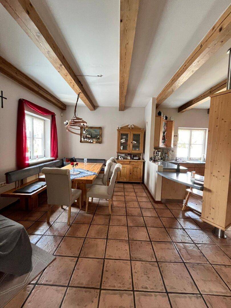 Heller Wohn- und Essbereich mit Holzbalken, Terrakottafliesen und traditionellen Möbeln.