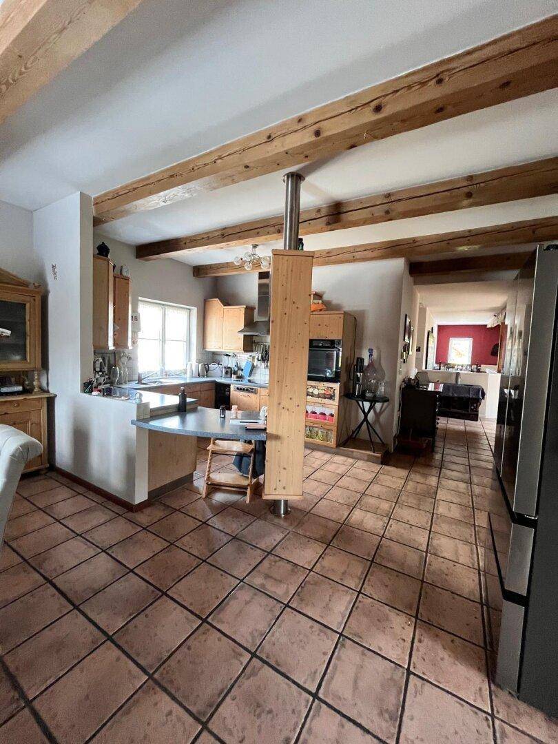 Offene Küche mit Holzschränken, Terrakottafliesen und Übergang zum Ess- und Wohnbereich.