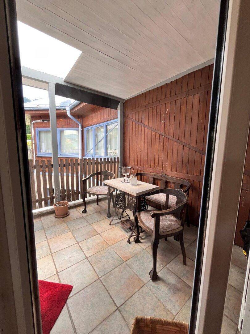Gemütliche überdachte Terrasse mit Sitzgelegenheiten und Holzwänden, ideal für entspannte Stunden.