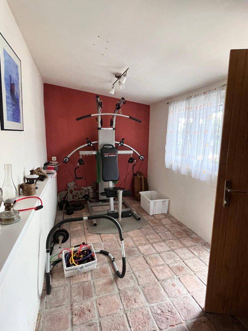 Fitnessraum mit Trainingsgeräten und Terrakottafliesen, ideal für das tägliche Workout zu Hause.