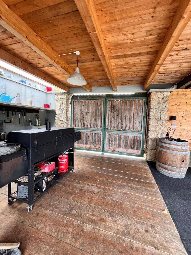 Überdachter Außenbereich mit Grillstation, Spülbecken und Holzboden, ideal für Sommerfeste.