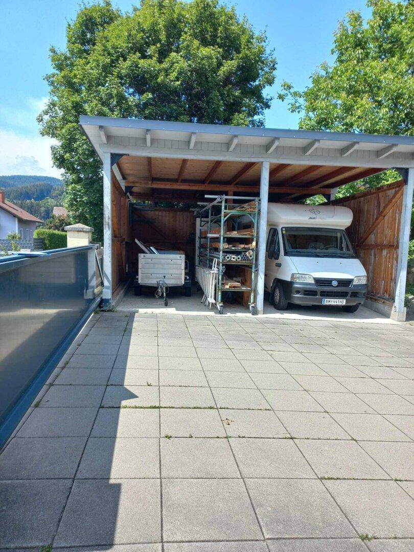 Überdachter Carport mit Stellplätzen für ein Wohnmobil und einen Anhänger.