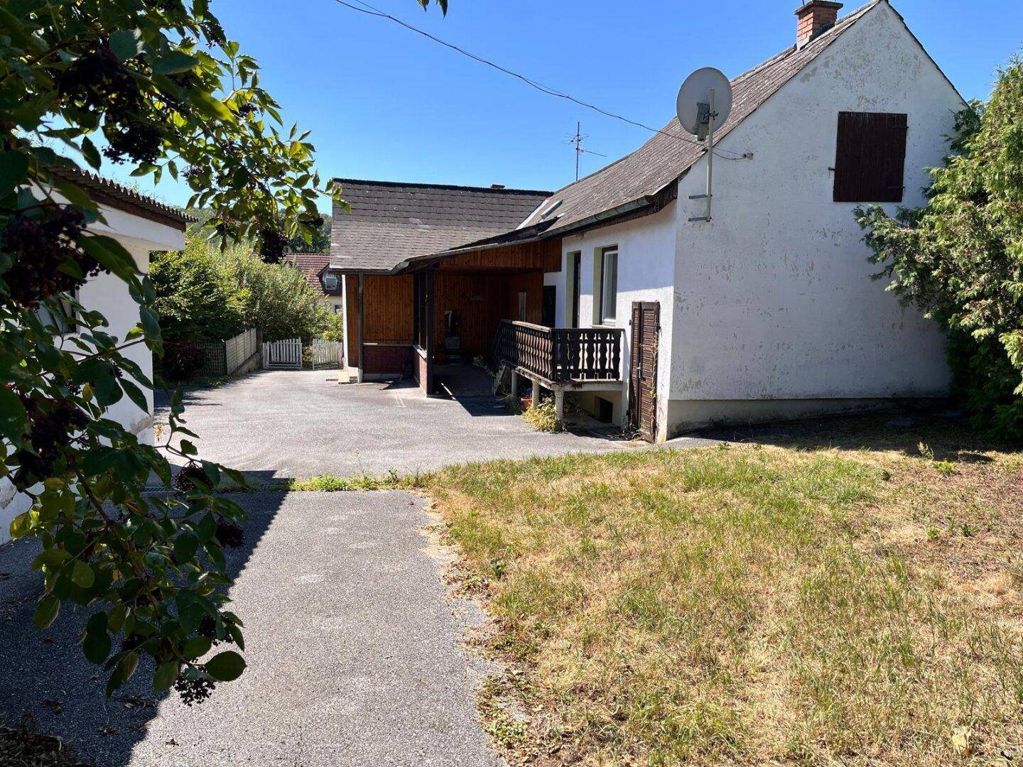 Gesamtansicht des ländlichen Hauses und des Grundstücks mit viel Grün und Nebengebäude.