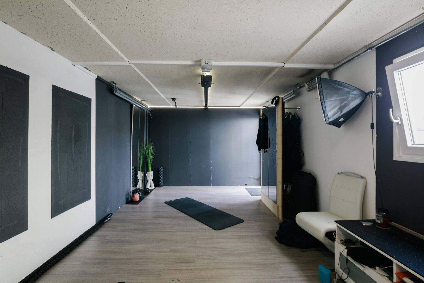 Fitnessraum im Keller mit viel Platz für Training, Spiegeln und minimalistischer Einrichtung.