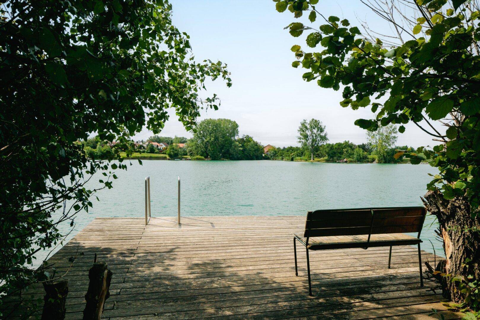 Hölzerner Steg mit Sitzbank und Badeleiter, bietet einen schönen Blick auf den See und die Natur.