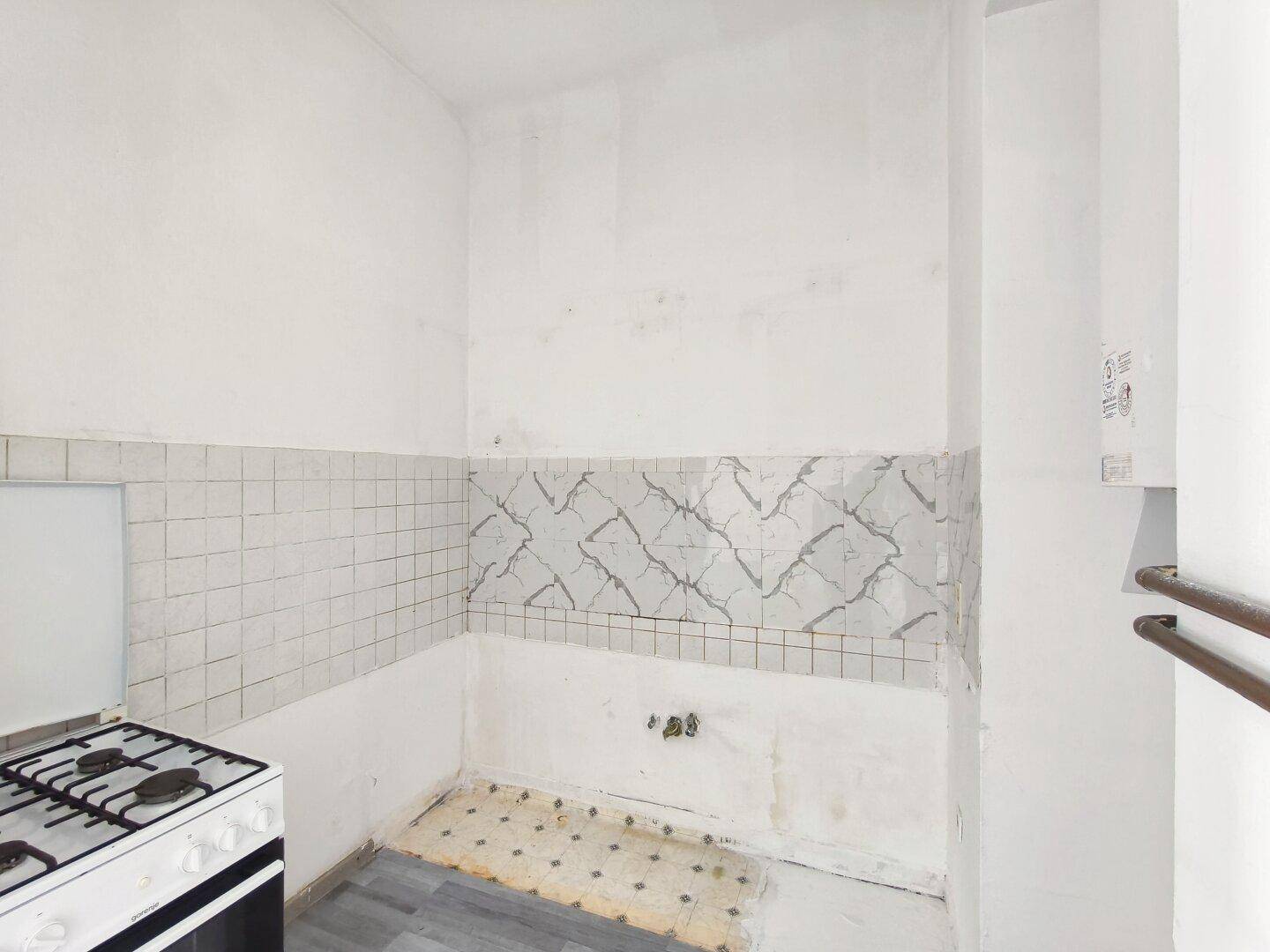 Einfache Küche mit Gasherd und gefliestem Bereich, bereit für eine Modernisierung.
