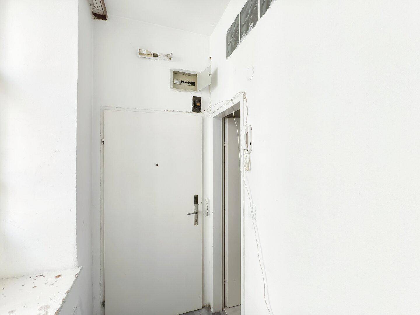 Eingangsbereich mit Wohnungstür und Gegensprechanlage, hell und funktional.