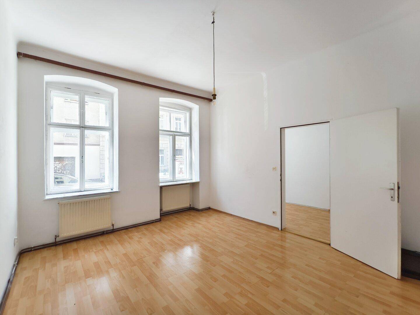Geräumiges, leeres Zimmer mit Holzboden und weiß gestrichenen Wänden, ideal für Wohnzwecke.