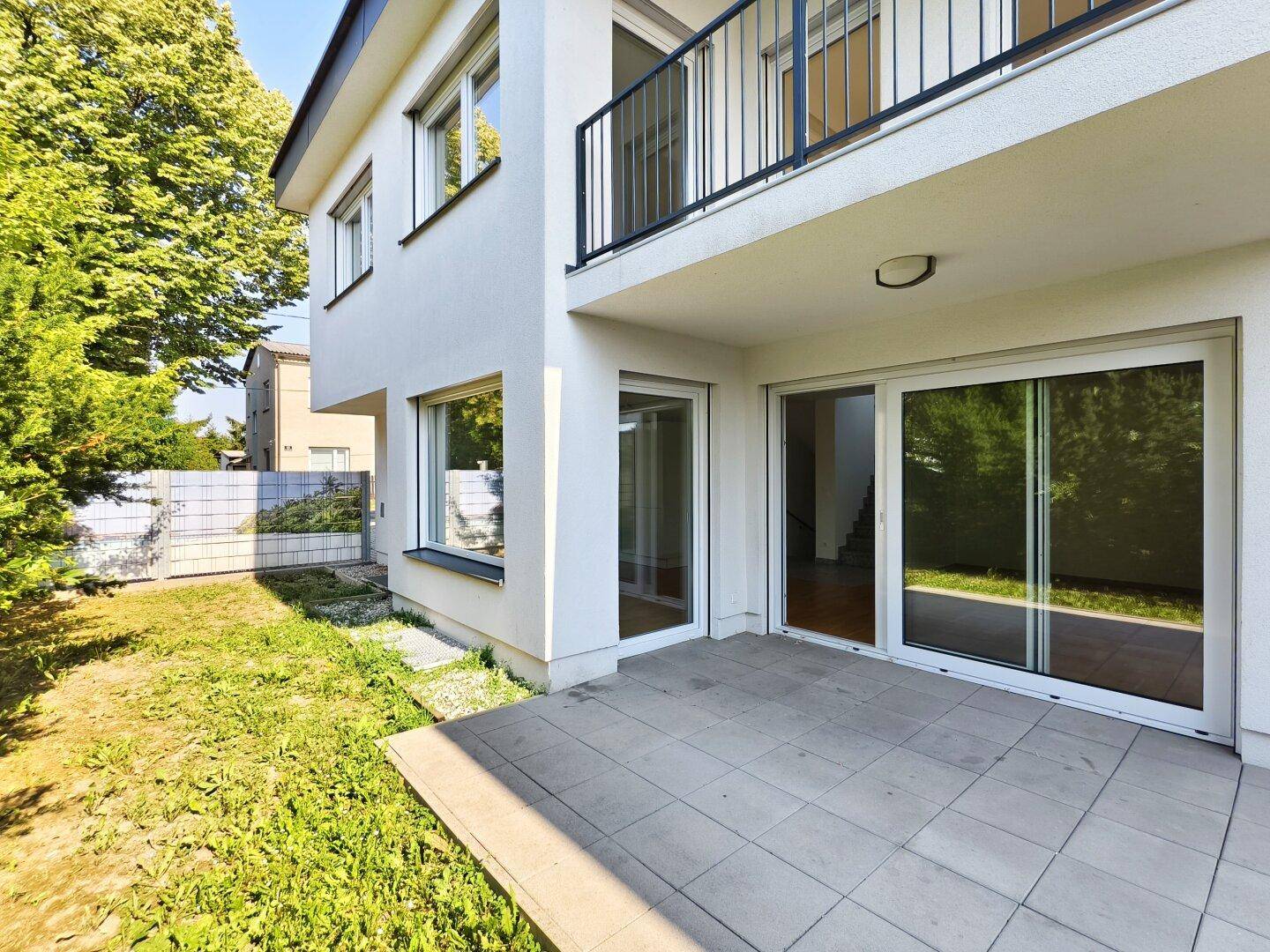 Ansicht der modernen Hausfassade mit großzügiger Terrasse und angrenzendem Garten.