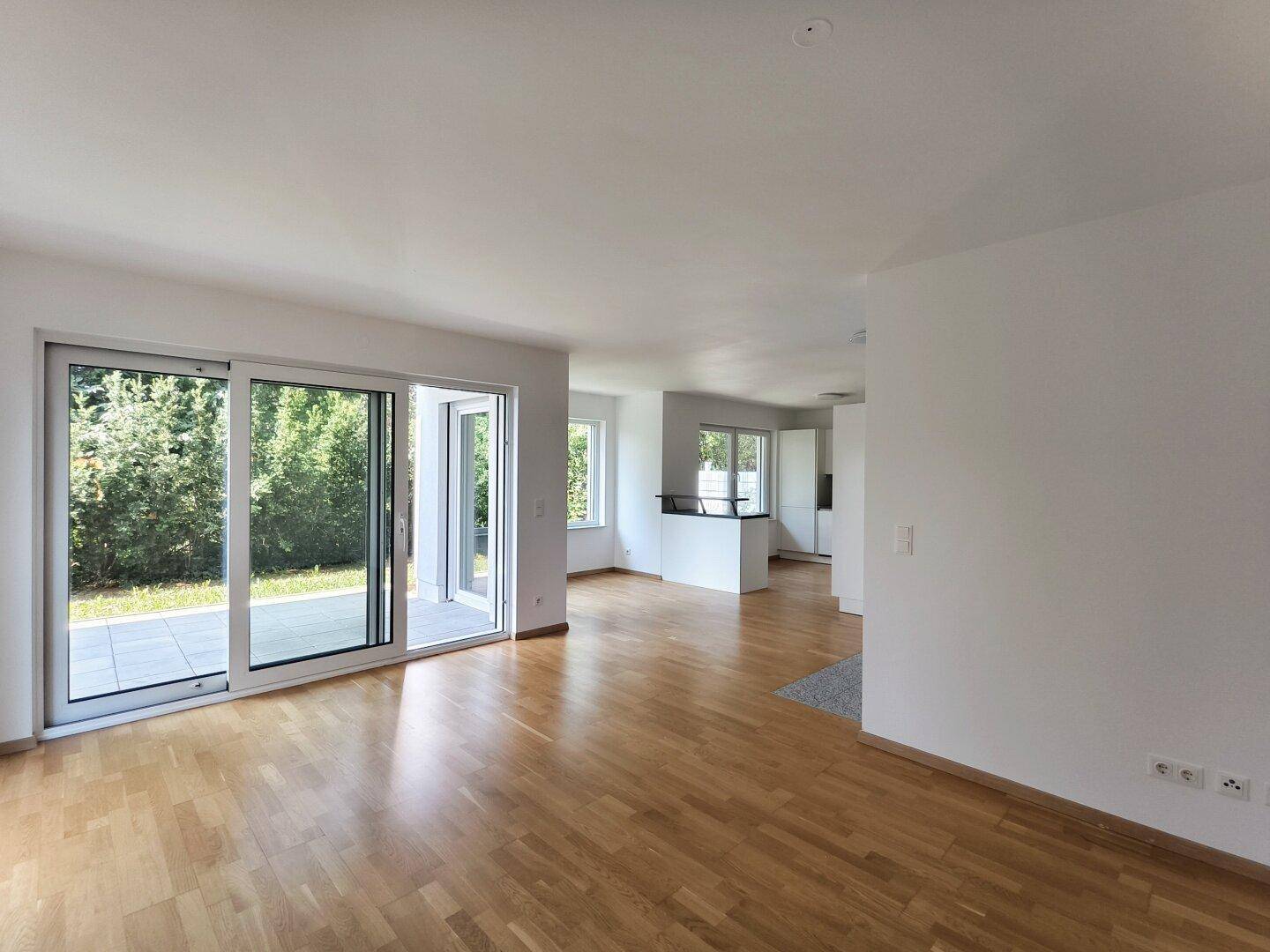 Heller Wohnbereich mit Holzboden und großen Schiebetüren, die zur Terrasse führen.